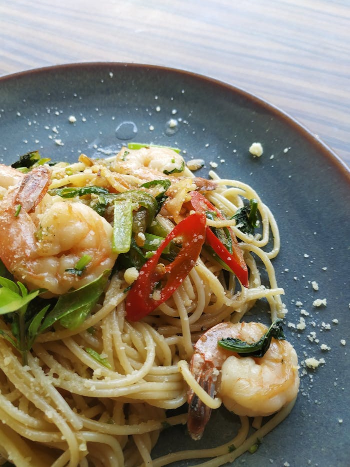 pexels-photo-2092906 Appetizing shrimp pasta garnished with fresh chili and herbs in a close-up view.